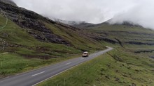 Aerial View Of Orange Land Rover Driving In Dramatic Landscape, Faroe Islands.