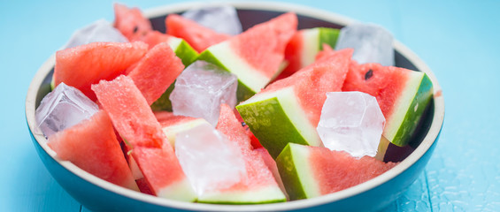 Wall Mural - slices of watermelon in a plate with ice on a blue background