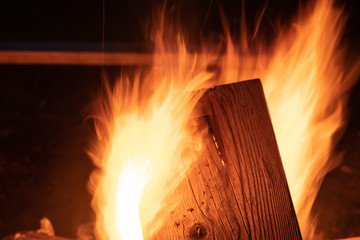 A wood fire blazes in a fire pit as family members and friends gather around at night to roast marshmallows