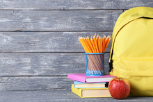 Yellow Backpack With School Supplies On Wooden Background