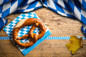 Brezel mit bayrischem Tischtuch auf Holzuntergrund