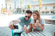 © Nebojsa - Portrait of young couple who taking selfie while sitting outdoors and eating ice-cream in cone