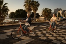 Senior Couple Riding Bicycle At Promenade
