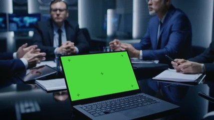 Wall Mural - On the Table Laptop Showing Green Mock-up Screen: Team of Politicians, Corporate Business Leaders and Lawyers Sitting at the Negotiations Table in the Conference Room, Trying to Come to an Agreement. 