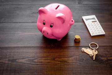 Money for buy car. Moneybox in shape of pig near keychain in shape of car, coins, calculator on dark wooden background copy space