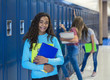 © Brocreative - Junior High school Student smiling in a school hallway. Black Female school girl smiling and having fun together during a break at school standing by her locker