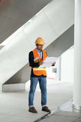 Canvas Print - Indian construction engineer in hardhat checking blueprint