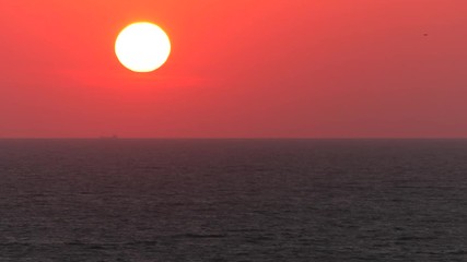 Wall Mural - Red sunset. The sun touches the horizon. Calm sea. Small waves.  Panning,Closeup, 