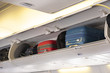 © structuresxx - Carry-on luggage on the top shelf in airplane