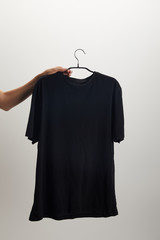 cropped image of woman holding hanger with black shirt isolated on white