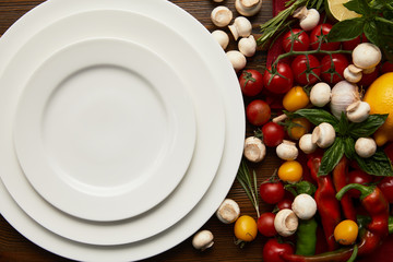 Wall Mural - top view of empty round white plates and fresh vegetables on wooden surface