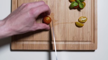 A chef cutting tomatoes on a wooden cutting board.
