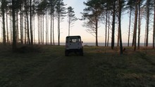 Aerial Drone Tracking Shot Of Land Rover Defender 90 Driving In Forest Towards Sea