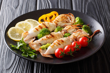 Healthy snack: grilled squid with tomatoes, broccoli, lemon and pepper closeup on a plate. horizontal