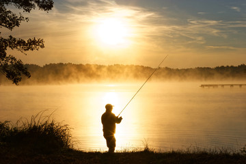 Silhouette of fisherman during foggy sunrise