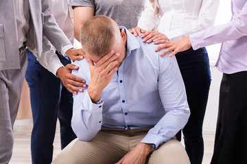Group Of People Consoling Upset Man