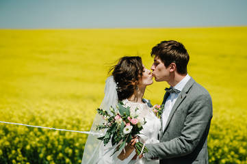 Wall Mural - The happy bride and groom hold the balloons and stand after wedding ceremony. A newlywed couple hugging and kissing on a country road in their honeymoon. photo.