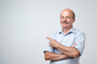 © Viktor Koldunov - Senior man in blue shirt pointing with index finger to important information on copyspace