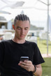 © sergiy1975 - young man looking into the phone while sitting at a table in a street cafe