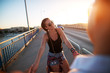 © dusanpetkovic1 - Young beautiful girl looking at her partner and holding his hands while they are crossing the bridge.