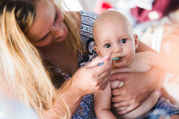 Wall Mural - Portrait of mother feeding her baby with spoon