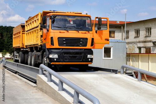 Fotomural orange truck with grain is weighed on the scales in the grain storage area