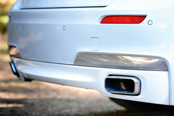 Wall Mural - Selective focus on parking sensor exhaust pipe bumper at rear of white luxurious car bumper close up on light  blurred background