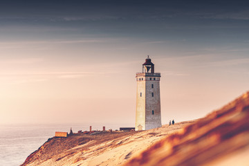 Wall Mural - Beautiful summer sunset over the sand dunes and famous lighthouse with ocean view. Rubjerg Knude Lighthouse, Lønstrup in North Jutland in Denmark, Skagerrak, North Sea