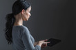 © Tierney - Young woman using her tablet on a gray background