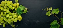 Fresh Green Grapes With Leaves Of Grapes. Top View. On A Black Wooden Background. Free Space For Text.