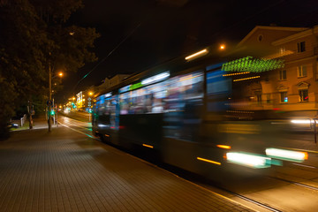 The motion of a blurred tram down the street in the evening.