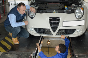 two auto mechanics discussing document in garage