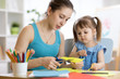 © Oksana Kuzmina - Teacher helping child girl to work with colored paper