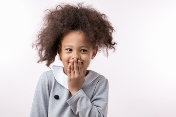 funny african kid closing her mouth and laughing at her crazy hairstyle. copy space. joy concept. have fun