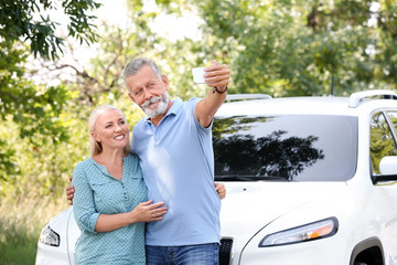 Poster - Happy senior couple taking selfie near car outdoors