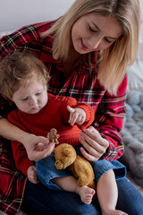 Wall Mural - Mother and toddler baby holding Christmas gingerman cookie at home. Red clothes, autumn season