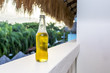 Cool refreshing bottle of lager or beer on a luxury tropical, caribbean hotel white washed balcony overlooking palm trees and resort
