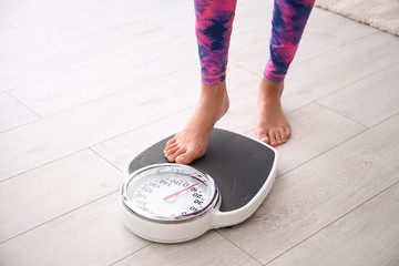 woman measuring her weight using scales on floor