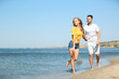 © New Africa - Happy young couple walking at beach on sunny day