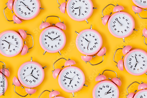 Fotomural Pink alarm clock on yellow background.