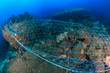 A huge abandoned ghost fishing net entangled over a large part of a tropical coral reef