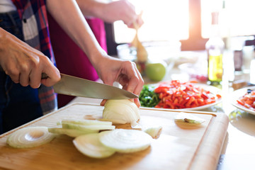 Pretty young woman cutting vegetables in the kitchen.