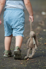 closeup of child walking in the street with plush rabbit in hand  dragging on the floor