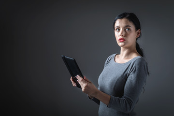 Young woman using her tablet on a gray background