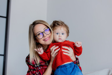 Wall Mural - Mother and toddler baby have a fun at home. Red clothes, autumn season