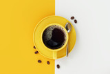 Top view of coffee cup on yellow and white background.