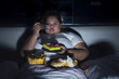 © Creativa Images - Overweight woman eating junk food in bed before sleeping