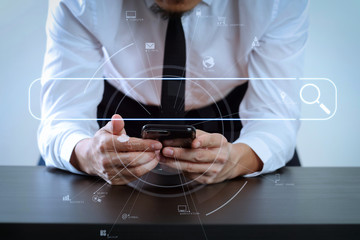 Wall Mural - close up of businessman working with smart phone on wooden desk in modern office with virtual icon diagram