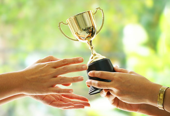 winner receive trophy on blur green background.