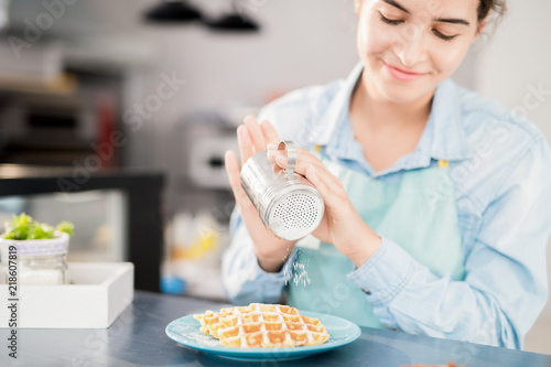 Fotografía Portrait of smiling young woman pouring cinnamon and powdered sugar over fresh w